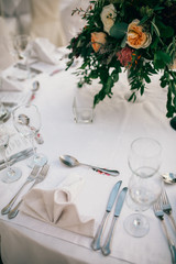 Table set for wedding or another catered event dinner. Catering in restaurant for wedding party. Served tables with pink and red flowers. 