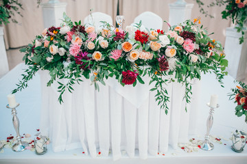 Table set for wedding or another catered event dinner. Catering in restaurant for wedding party. Served tables with pink and red flowers. 