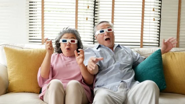 Senior man and woman wearing 3d glasses for watch movie at home. Senior couple watch movie with excite emotion together. People with lifestyle, holidays, entertainment concept. 4k resolution.