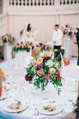 Table set for wedding or another catered event dinner. Catering in restaurant for wedding party. Served tables with pink and red flowers. 