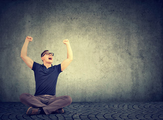 Cheerful man screaming happily with hands raised