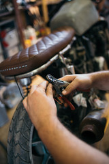 Close up shot of experienced man working in custom made motorcycle workshop.