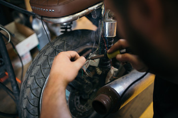 Close up shot of experienced man working in custom made motorcycle workshop.