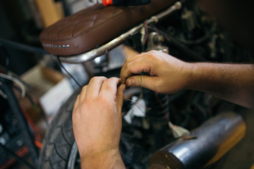 Close up shot of experienced man working in custom made motorcycle workshop.