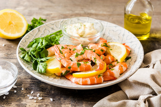 Grilled shrimps, parsley and lemon on wooden table