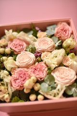 a bouquet of small pink and peach roses with greens