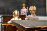 Concept of public primary school education with young boy and girl listening to the female teacher