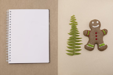 Ginger bread cookies on craft background. Blank notepad with leaf of fern. Christmas mockup. Top view.