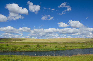 Sunny summer landscape with river,fields,green hills and beautiful clouds in blue sky.River Upa in Tula region,Russia. 