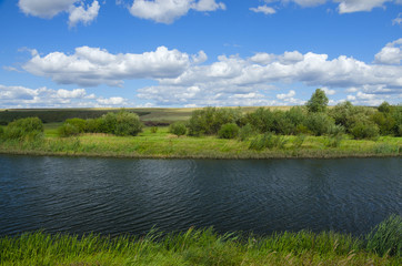 Sunny summer landscape with river,fields,green hills and beautiful clouds in blue sky.River Upa in Tula region,Russia. 