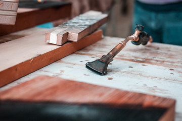 Artisan and carpenter burning wood planks, focus on the gas burner pistol, made of brass and orange...