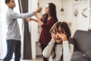 Little girl crying because of her parents quarreling. Girl abused with mother and father shouting and conflict angry background in home. Family dramatic scene, Family social issues problem concept.