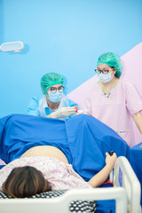Maternity ward,obstetrician and nurse to the patient lying on a bed in the delivery room