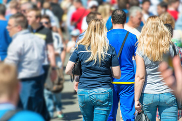 Obraz premium Crowd of people walking on city street with young woman with long hair in centre