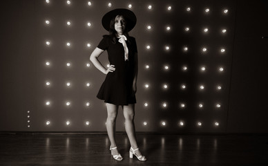 Girl in black dress and black hat posing on red background