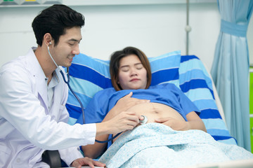 Young preganant woman expecting a baby doctor visit. Cropped image of doctor using stethoscope examining pregnant woman