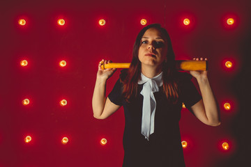 girl posing on a red background with a baseball bat in his hands, the concept of a bully or athletes