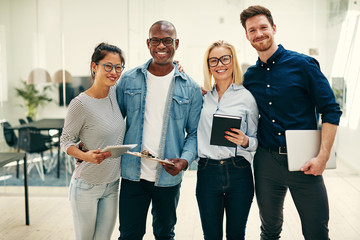 Smiling team of young businesspeople standing together in an off