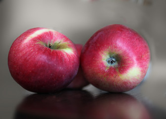 Three red ripe apples lying on a table