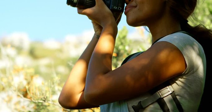 Female hiker clicking photos with digital camera 4k