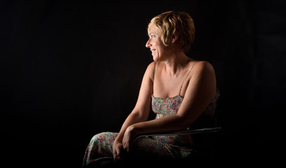  portrait of middle aged woman sitting on a chair on black