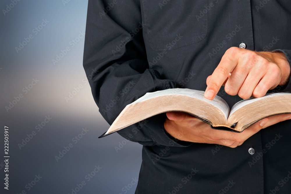 Wall mural Man reading old heavy book on background