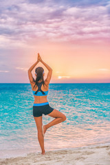 Fototapeta na wymiar Yoga meditation woman meditating at beach sunset relaxing in yoga posture, tree pose, vrksasana. Relaxed serene Asian woman enjoying evening sun light and sunshine