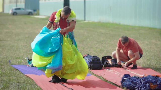 An adult man folds his parachute