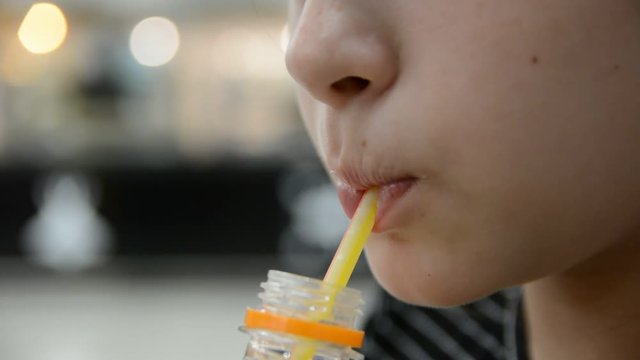 Cute little child girl drinking a juice from straw sitting in restaurant