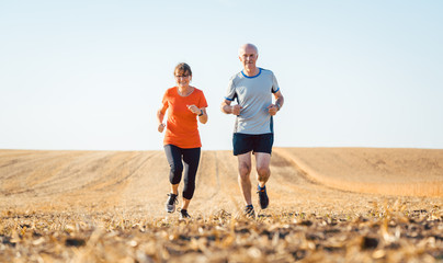 Senior Frau und Mann beim Jogging über ein Feld