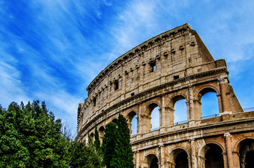 Naklejka na ściany i meble The ancient arches of the Colosseum against the blue sky with white traces from the floating clouds. Rome. Italy 