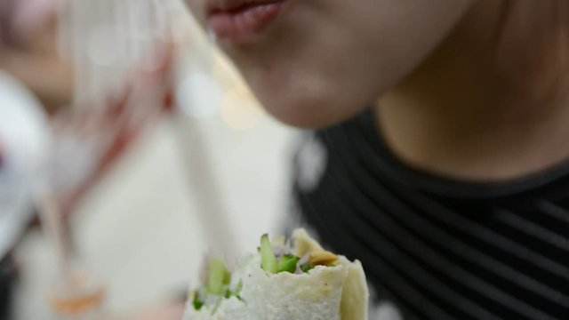 A beautiful girl eating a burrito, close up