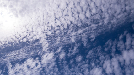 A big blue separation in the middle of a lot of small puffy clouds during a beautiful sunny day.