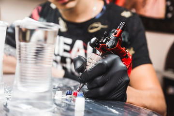 The tattoo artist creates a picture on the body of a man. close-up of tattoo machines and paints