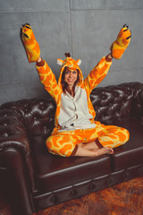 Pajamas for Halloween in the form of a kangaroo. Emotional portrait of a girl on a sofa background....