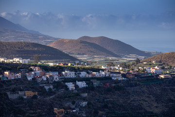 Colorful houses in the background of three volcanoes and a blue sky with clouds. La Palma Canary Islands.