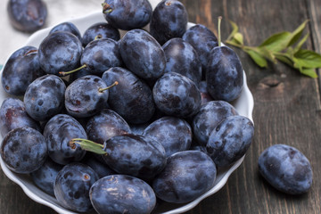 Berries plum in a plate on a wooden table