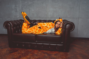 Pajamas for Halloween in the form of a kangaroo. Emotional portrait of a girl on a sofa background....