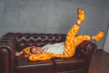 Pajamas in the form of a kangaroo. emotional portrait of a student on the background leather sofa....
