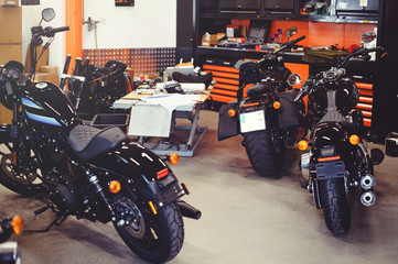 Obraz premium Wiele motocykli na podłodze z narzędziami warsztatowymi, nowoczesny garaż, magazyn i naprawa. Ten rower będzie idealny. naprawa motocykla w warsztacie