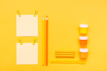 Stationery - sheets for notes clipped, pencil, felt-tip pen,  gouache, plasticine and stack on a yellow background. Top View