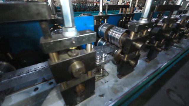 Profiles are created on the metal rolling machine at the plant. creation of profiles, machine for creation of steel profiles from steel sheet. close-up