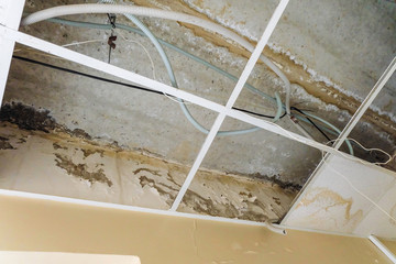 Damaged suspended ceiling with water leaks on wall and floor slabs