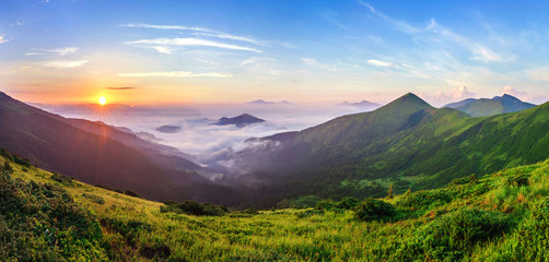 Beautiful sunrise in mountains with white fog below panorama