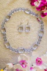 Clear plastic necklace and earrings  handmade next to colorful flowers on a fur surface