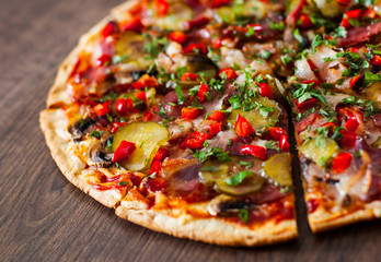 sliced Pizza with Mozzarella cheese, mushrooms, salami, bacon, Tomatoes, pepper, Spices and Fresh Basil. Italian pizza on wooden background.