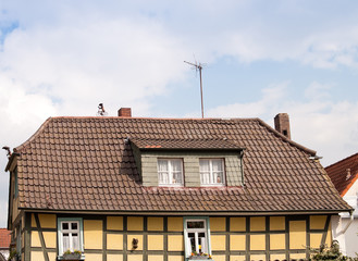 Timber framed house with two figurines on roof