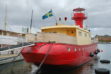 Fototapeta premium Cityscape of Stockholm, Sweden. Vintage ship of red color at the foreground. Swedeish flag on the boat.