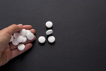 Close up white pills in hand isolated on black background. Medicine, narcomania, treatment.