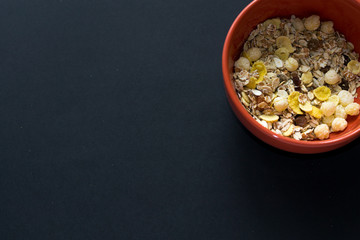 Obraz na płótnie Canvas Close up muesli in ceramic red bowl isolated on black background. Heathy food, breakfast.